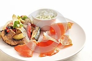 Smoked salmon with vegetables and dip on a white plate, healthy snack with low calories for a slimming diet, selected focus