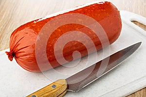 Smoked sausage, knife on cutting board on wooden table