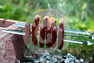 Smoked sausages are fried on a fire on coals