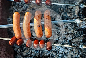 Smoked sausages are fried on a fire on coals