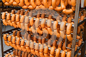 Smoked sausages hanging on a metal frame in the smokehouse.