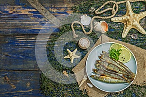 Smoked smelt with fresh lemon and herbs. Salted fish with marine decor. Trendy dish, sea rope