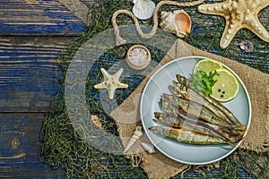 Smoked smelt with fresh lemon and herbs. Salted fish with marine decor. Trendy dish, sea rope