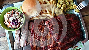 Smoked Texas bbq pork ribs and belly with coleslaw and fries top view