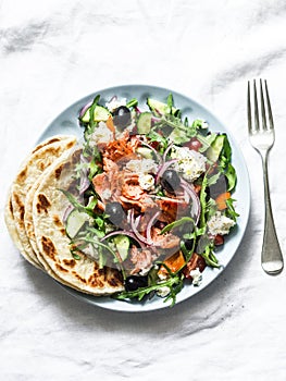 Smoked trout greek salad on a light background, top view. Healthy mediterranean diet food