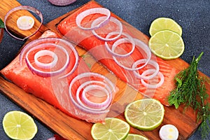 Smoked trout with salmon, red fish steak, served with herbs, onions, lemon. Salmon cooking, seafood, healthy natural food,