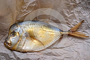 Smoked vomer fish on crumpled parchment on the table.
