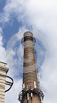 Smokestack of an industrial plant against a blue sky with clouds