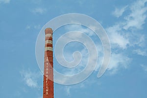 Smokestack in shape of wine bottle neck with text In vino veritas. Industrial chimney on cloud sky background with copy space. photo