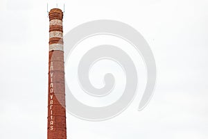 Smokestack in shape of wine bottle neck with text In vino veritas. Industrial chimney on isolated background. Manufacturing of photo