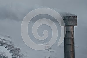 Smokestack with Smoke column and snow covered mountains