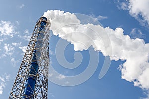 Smokestack and steam on blue sky background