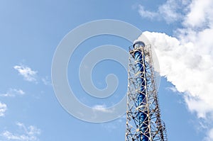 Smokestack and steam on blue sky background