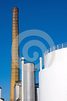 Smokestack and white industrial tank