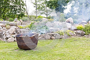Smoking cauldron in a garden in summer