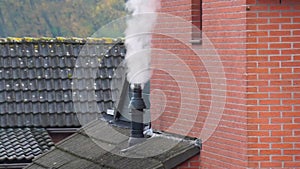 Smoking chimney on a dutch rooftop during winter, warming the house