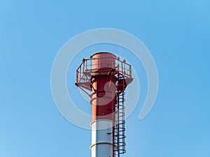 The smoking chimney of the enterprise against the blue sky