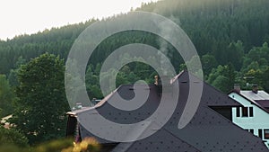 Smoking chimney of a rural cottage house in the woods on the background of mountains