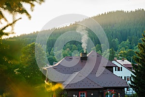 Smoking chimney of a rural cottage house in the woods on the background of mountains