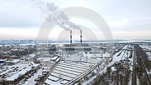 Smoking chimneys on power station on winter city. Aerial view industrial pipes