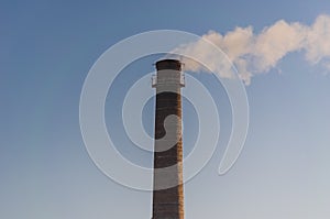 Smoking factory chimney made of brick.