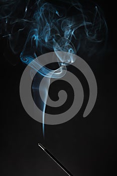 Smoking incense stick with smoke going up on Black Background. Pure relaxation theme, smoke steam, smoke waves, fog and mist