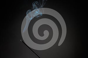 Smoking incense stick with smoke going up on Black Background. Pure relaxation theme, smoke steam, smoke waves, fog and mist