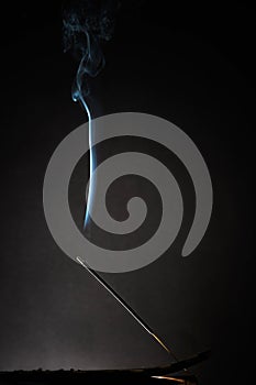 Smoking incense stick with smoke going up on Black Background. Pure relaxation theme, smoke steam, smoke waves, fog and mist