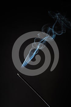 Smoking incense stick with smoke going up on Black Background. Pure relaxation theme, smoke steam, smoke waves, fog and mist