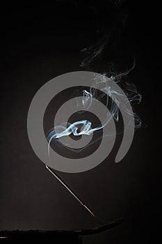 Smoking incense stick with smoke going up on Black Background. Pure relaxation theme, smoke steam, smoke waves, fog and mist