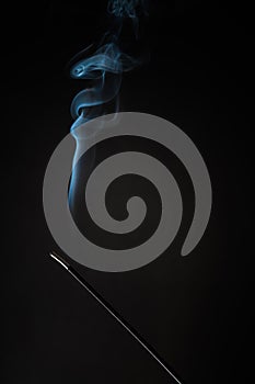 Smoking incense stick with smoke going up on Black Background. Pure relaxation theme, smoke steam, smoke waves, fog and mist