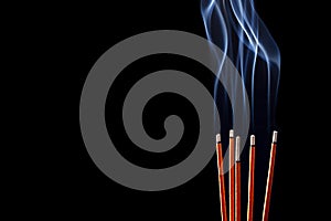 Smoking incense sticks on black background