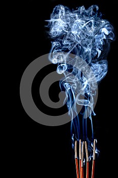 Smoking incense sticks on black background