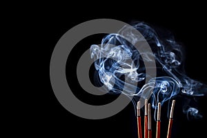 Smoking incense sticks on black background