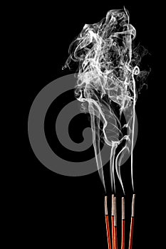 Smoking incense sticks on black background