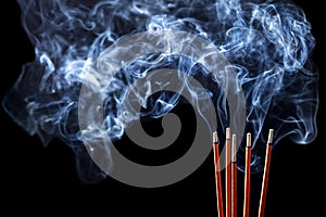 Smoking incense sticks on black background