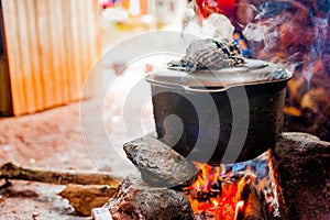 Smoking iron pot above fire in traditional african kitchen in cameroon during cooking