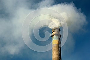 Smoking pipe of thermal power plant with Ukrainian flag colors against blue sky near Kharkiv, Eastern Ukraine