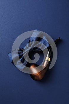 Smoking pipe and tie bow on blue background