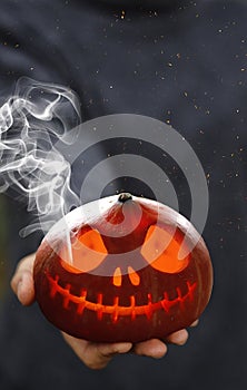 A Smoking pumpkin in a man`s hand. Big spooky helloween symbol. Selective focus