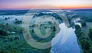 Smoky morning mist over the river. Beautiful panoramic view of river and green banks of the river in the early summer morning