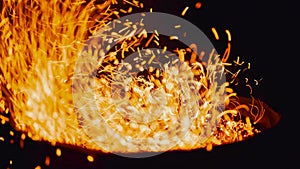 Smoldering bonfire. Close-up of flying sparks on a black background. Fire flames and sparks.