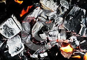 Smoldering embers of fire, live coals, burning charcoal in the background texture, closeup, glowing coal