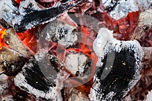 Smoldering embers of fire, live coals, burning charcoal in the background texture, closeup, glowing coal