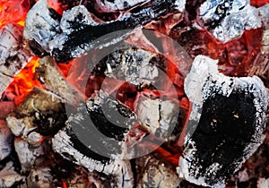 Smoldering embers of fire, live coals, burning charcoal in the background texture, closeup, glowing coal