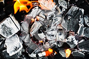 Smoldering embers of fire, live coals, burning charcoal in the background texture, closeup, glowing coal