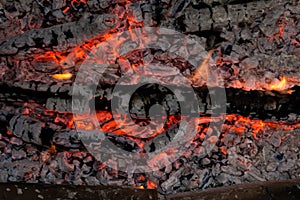 Smoldering embers of fire, live coals, burning charcoal in the background texture, closeup, glowing coal