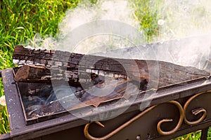 Smoldering firewood and embers in a steel brazier