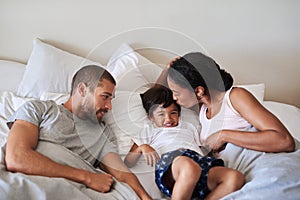 Smooches galore for my little bean. a beautiful young family of three spending time together in their bedroom at home.