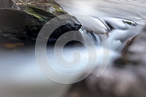 Smooth creek water flowing between the large rocks